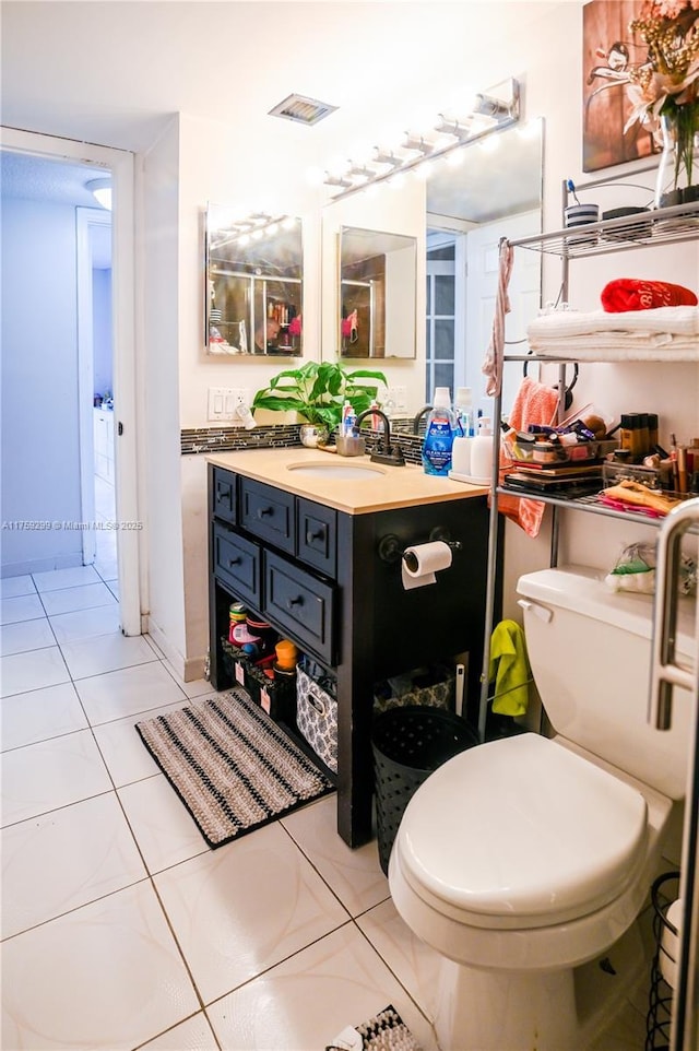 bathroom with toilet, vanity, tile patterned flooring, and visible vents