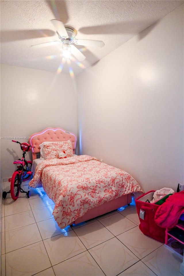 bedroom with a textured ceiling, ceiling fan, and light tile patterned floors