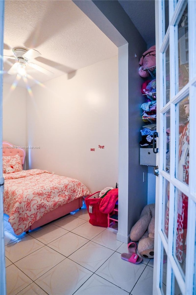 bedroom featuring a ceiling fan, tile patterned flooring, and a textured ceiling