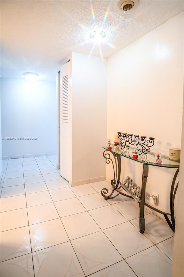 hall featuring light tile patterned flooring and a textured ceiling