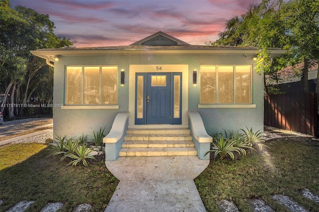 exterior entry at dusk featuring stucco siding