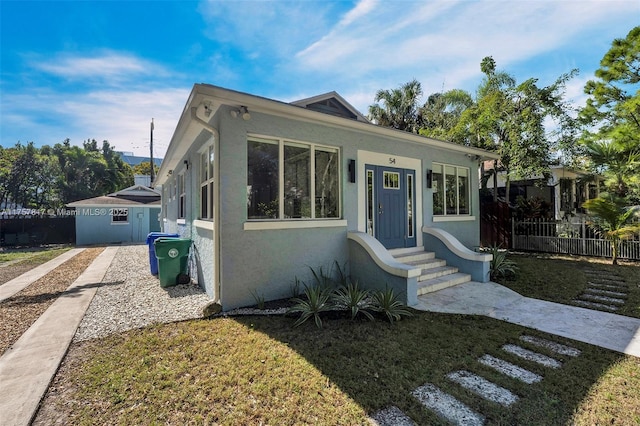 bungalow-style house with entry steps, fence, and stucco siding