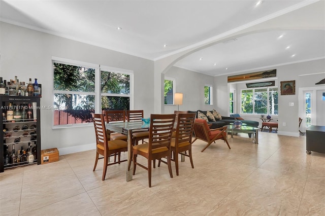 dining space featuring arched walkways, ornamental molding, and baseboards