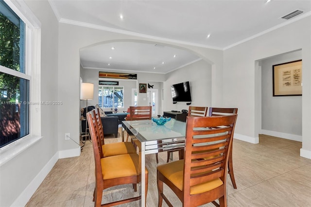 dining area featuring arched walkways, ornamental molding, visible vents, and baseboards