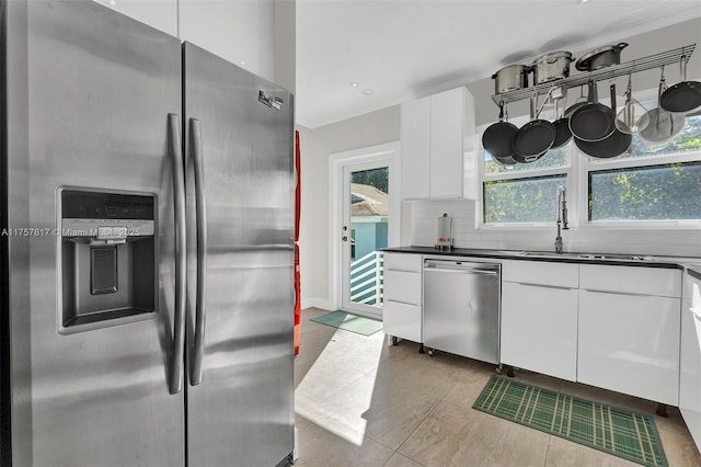 kitchen with stainless steel appliances, dark countertops, white cabinets, and decorative backsplash