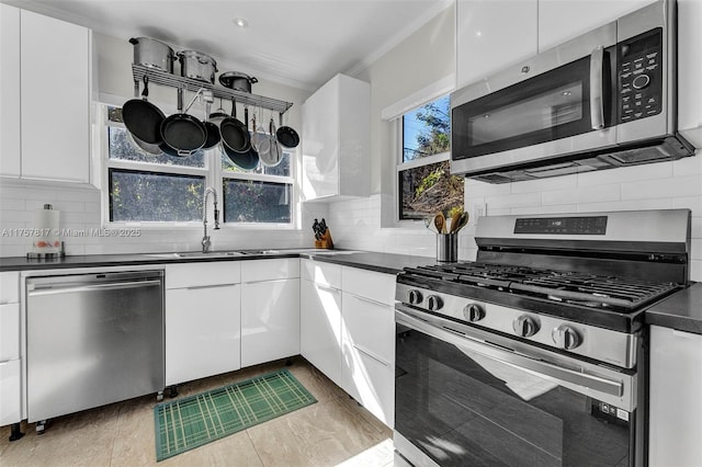 kitchen featuring dark countertops, appliances with stainless steel finishes, white cabinets, and backsplash