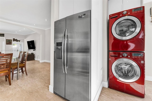 laundry area with arched walkways, ornamental molding, stacked washing maching and dryer, laundry area, and baseboards