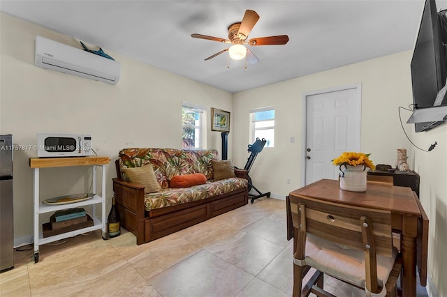 living room featuring light tile patterned floors, ceiling fan, baseboards, and a wall mounted air conditioner