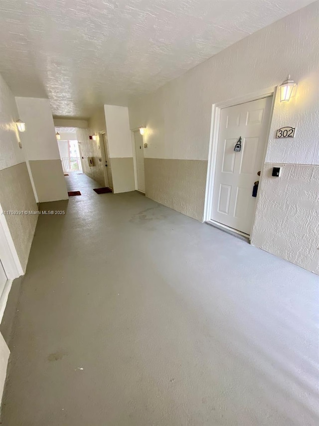 unfurnished living room featuring a textured ceiling, concrete floors, and a textured wall