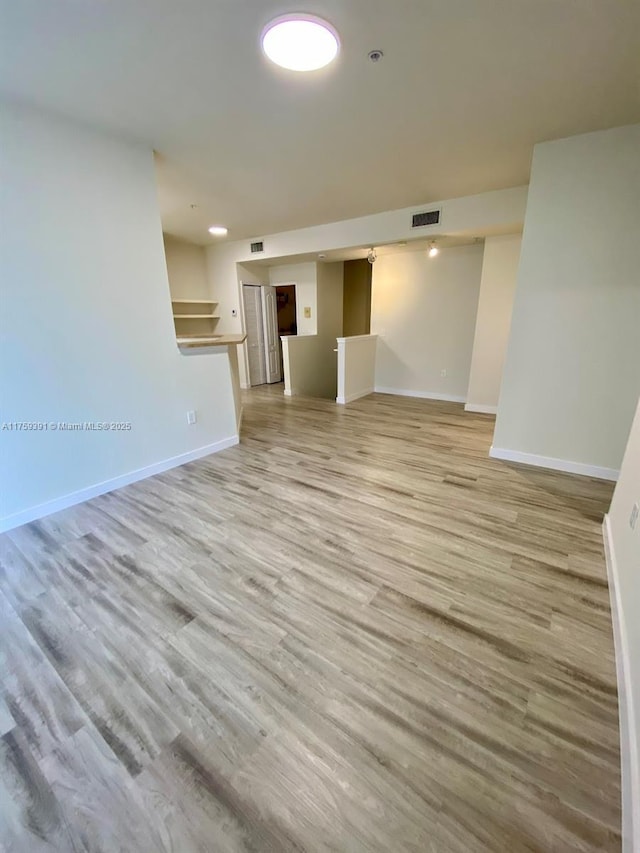 spare room featuring baseboards, visible vents, and light wood-type flooring