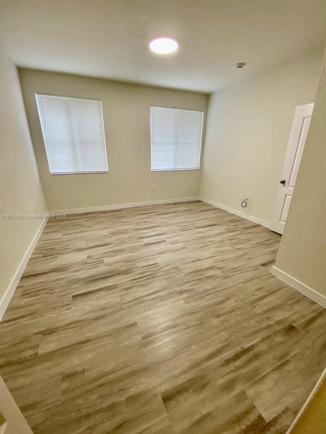 empty room with baseboards and light wood-style flooring