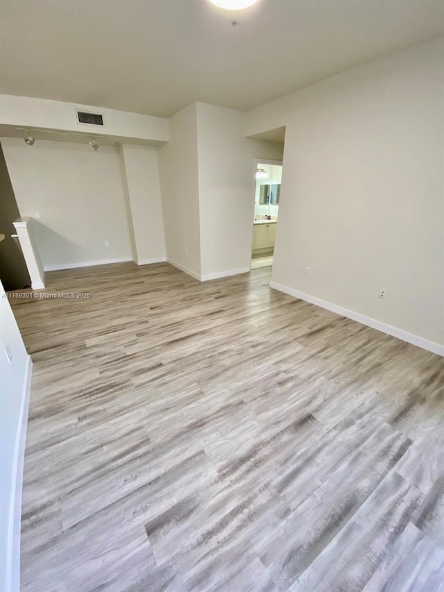 empty room with visible vents, baseboards, and wood finished floors