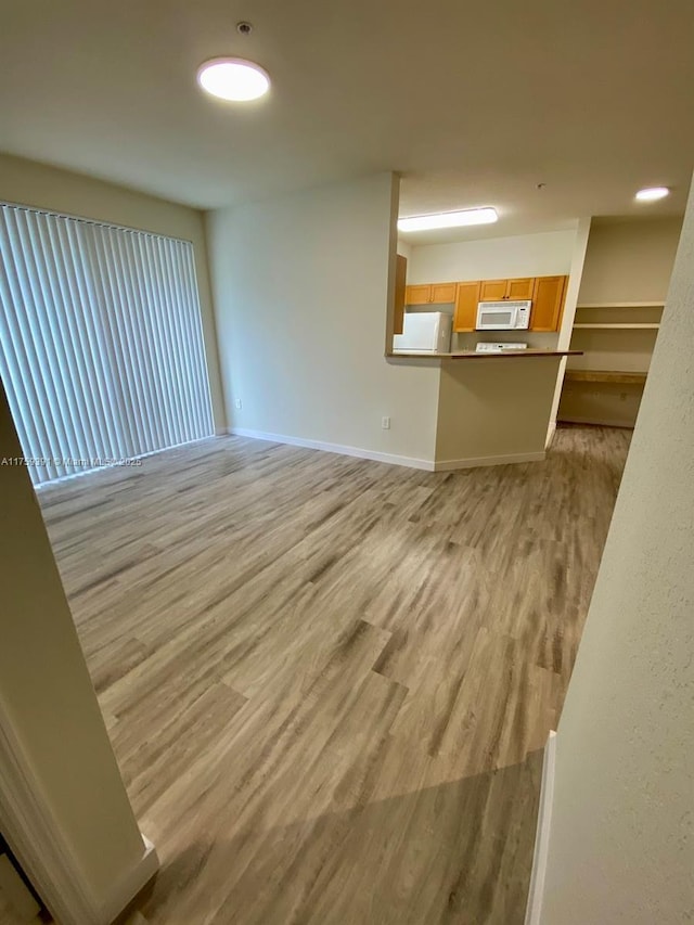 unfurnished living room with light wood-style flooring and baseboards