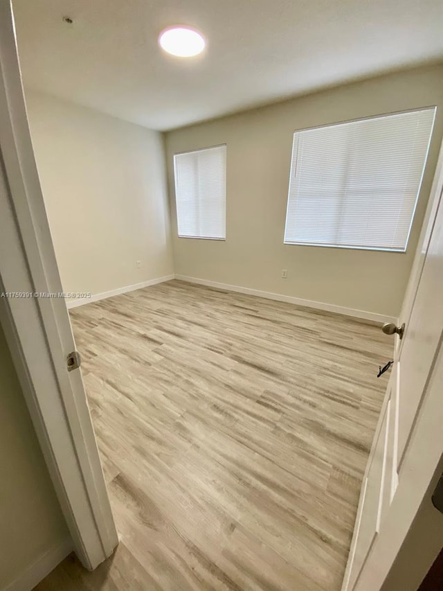 unfurnished room featuring baseboards and light wood-style floors