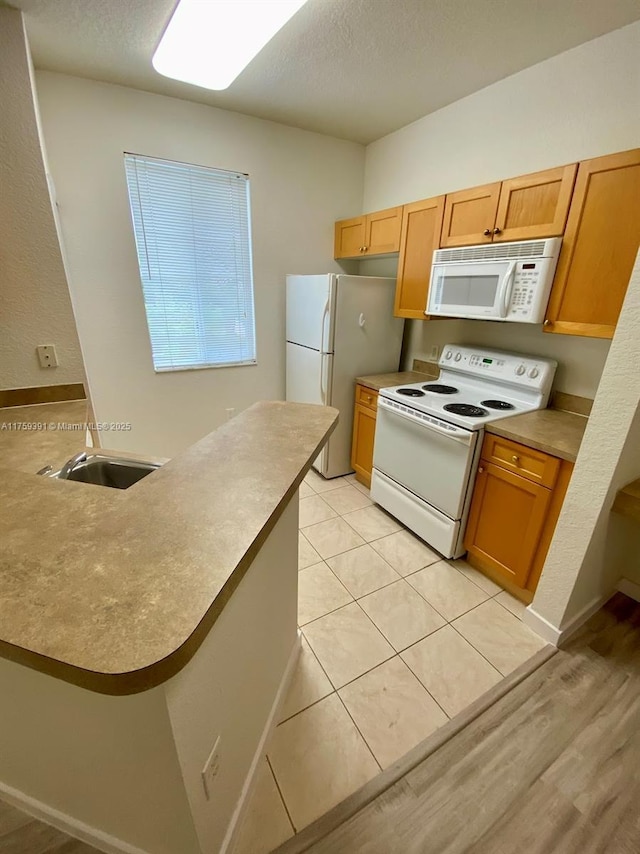 kitchen featuring light tile patterned floors, white appliances, a textured ceiling, and a sink