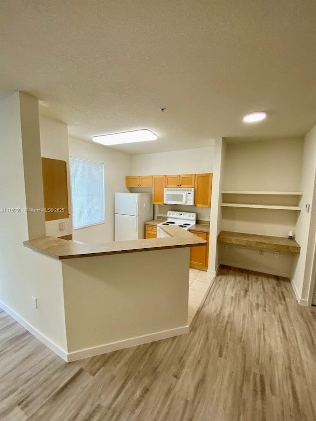 kitchen featuring baseboards, white appliances, light wood-style floors, and a textured ceiling