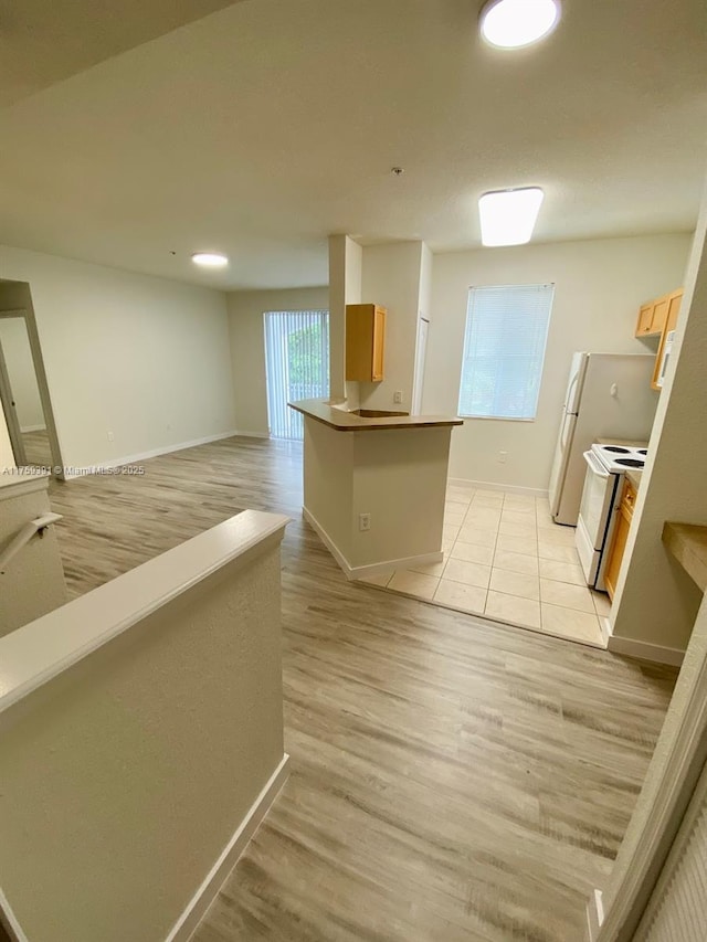 kitchen with baseboards, light wood-style floors, open floor plan, and white range with electric stovetop