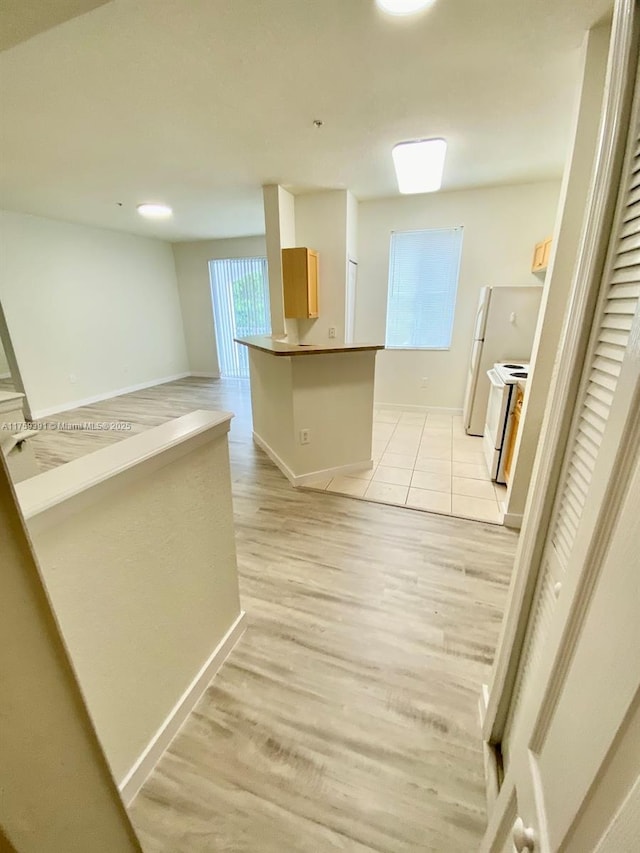 hall featuring baseboards and light wood-type flooring