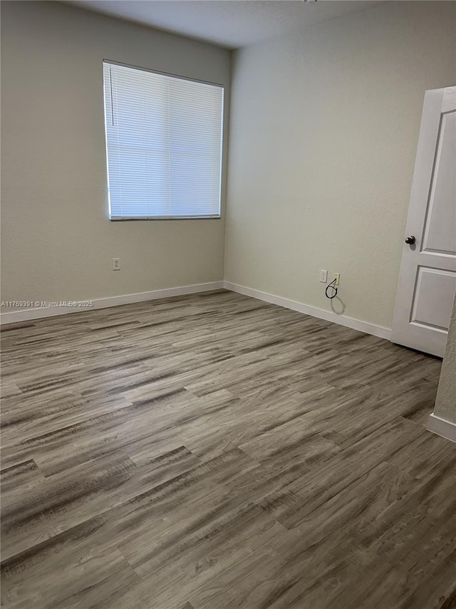 empty room with baseboards and wood finished floors