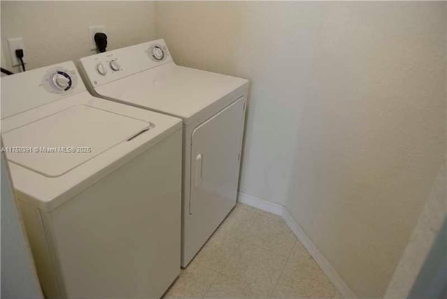 clothes washing area featuring baseboards, separate washer and dryer, and laundry area