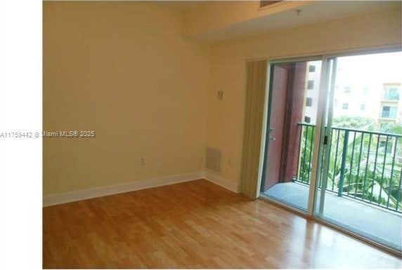 unfurnished room featuring baseboards, wood finished floors, and a healthy amount of sunlight