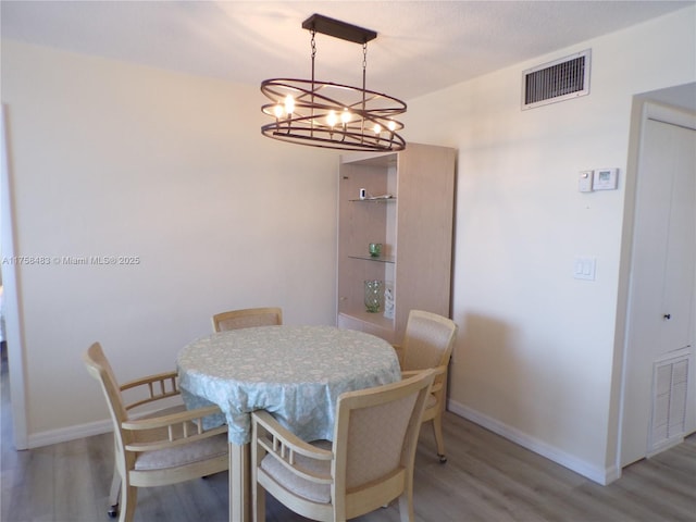 dining area with light wood-type flooring, visible vents, and baseboards