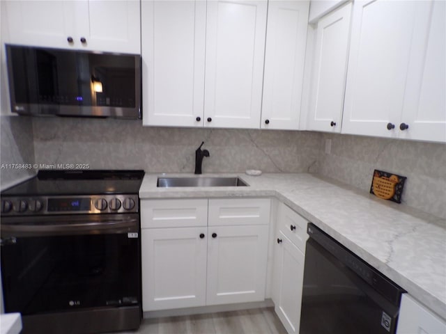 kitchen with appliances with stainless steel finishes, white cabinets, a sink, and backsplash