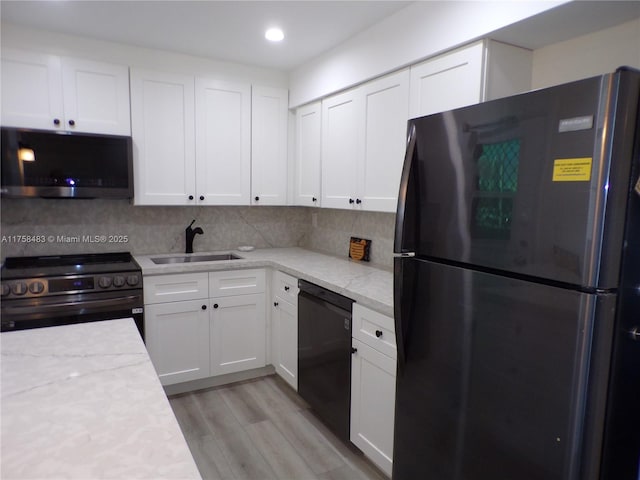 kitchen with white cabinets, black appliances, decorative backsplash, and a sink