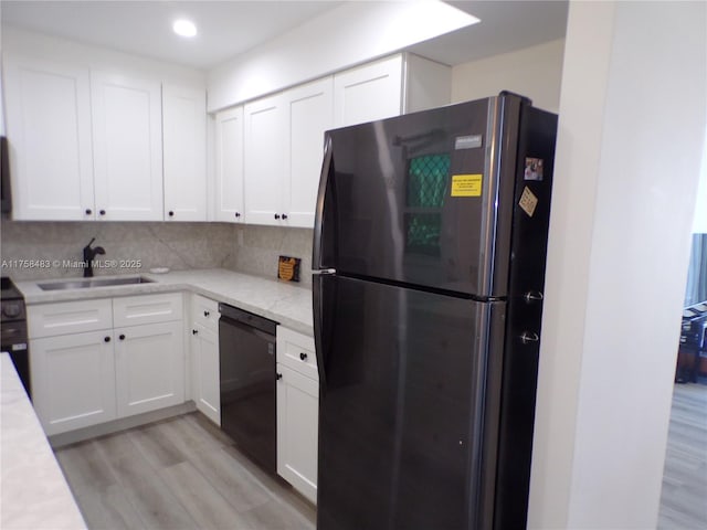 kitchen featuring light wood finished floors, freestanding refrigerator, white cabinetry, a sink, and dishwasher