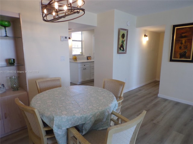 dining space featuring light wood-style floors, a notable chandelier, and baseboards