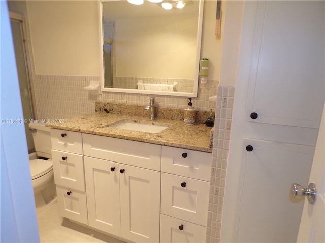 bathroom with toilet, tile patterned floors, vanity, and tile walls