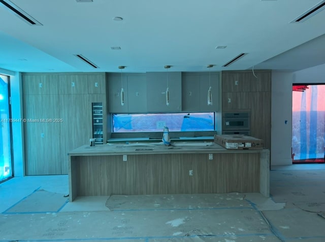 kitchen featuring wall oven, visible vents, pendant lighting, and a sink