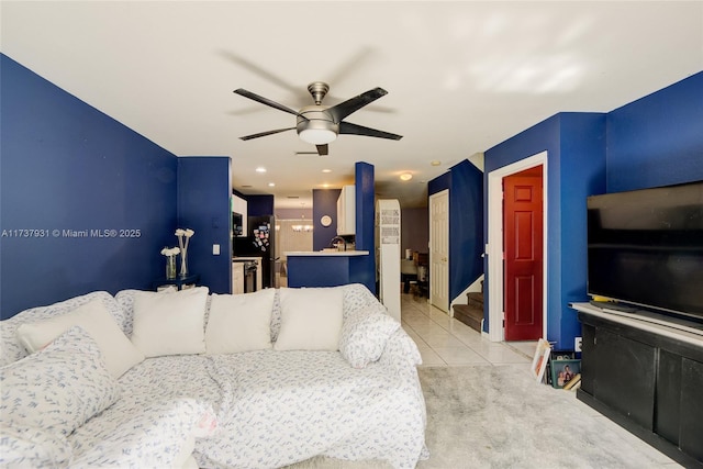 living area featuring light carpet, stairway, a ceiling fan, and light tile patterned flooring