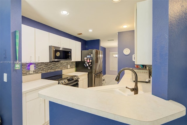 kitchen with stainless steel appliances, a sink, white cabinetry, light countertops, and decorative backsplash