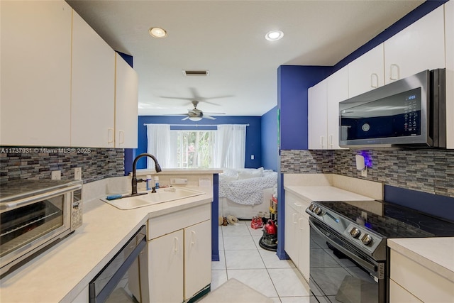 kitchen with dishwashing machine, a sink, light countertops, black electric range oven, and stainless steel microwave