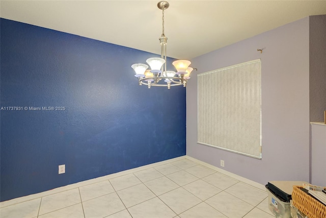 tiled spare room with a chandelier