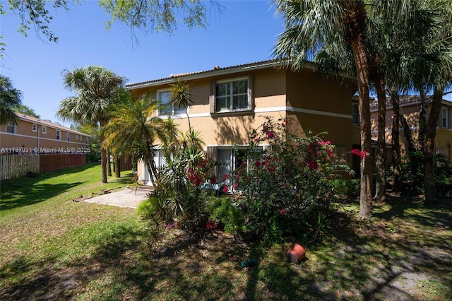 rear view of property featuring a yard, a patio, fence, and stucco siding