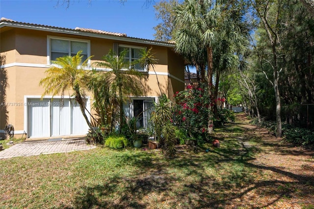 back of house featuring a lawn and stucco siding