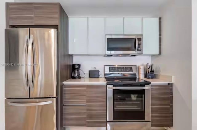 kitchen featuring white cabinets, modern cabinets, appliances with stainless steel finishes, and light countertops