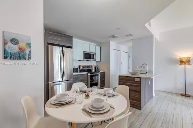 dining space featuring light wood-style floors and visible vents