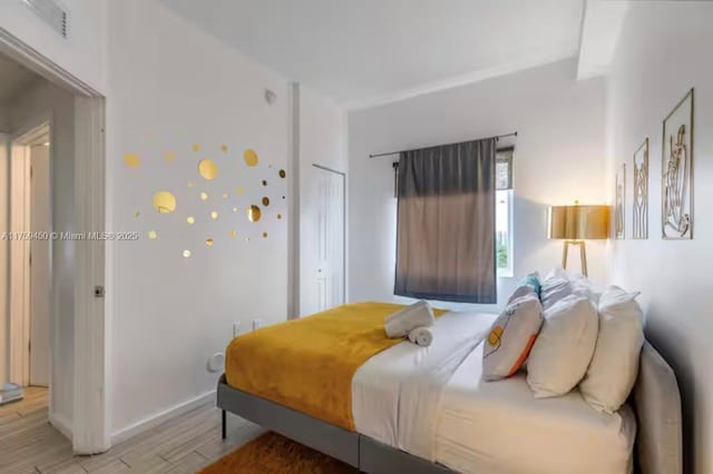 bedroom with light wood finished floors, a closet, visible vents, and baseboards