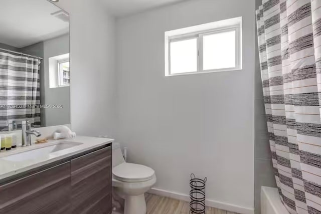 full bathroom featuring toilet, plenty of natural light, baseboards, and vanity