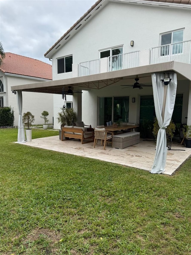 back of property featuring a yard, a patio, outdoor lounge area, and a balcony