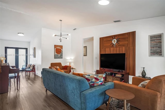 living area featuring baseboards, visible vents, dark wood finished floors, vaulted ceiling, and a notable chandelier