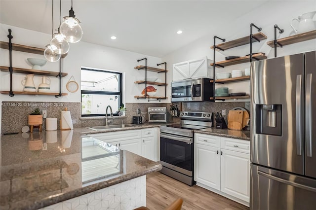 kitchen with stainless steel appliances, white cabinetry, a sink, and open shelves