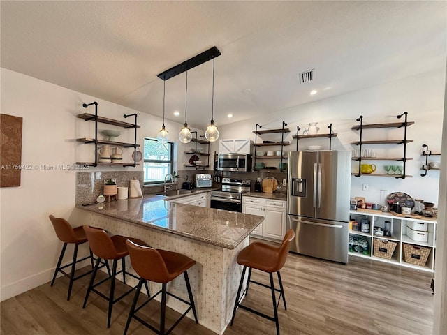 kitchen featuring stainless steel appliances, visible vents, a peninsula, and open shelves