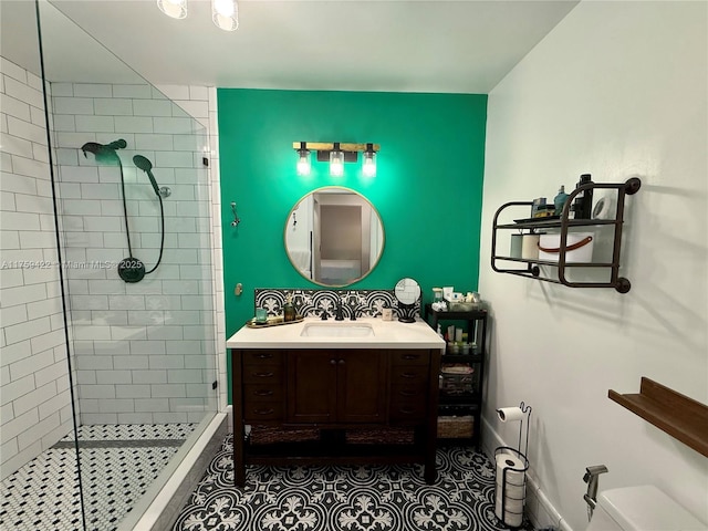 bathroom featuring toilet, a tile shower, vanity, and baseboards