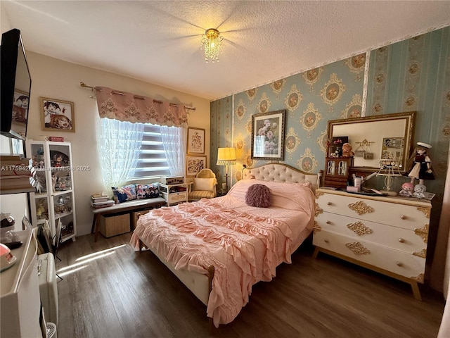 bedroom with wallpapered walls, a textured ceiling, and wood finished floors