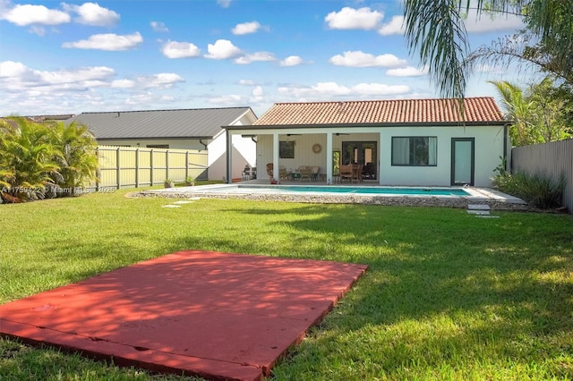 rear view of house with ceiling fan, a fenced backyard, a tiled roof, a yard, and a patio area