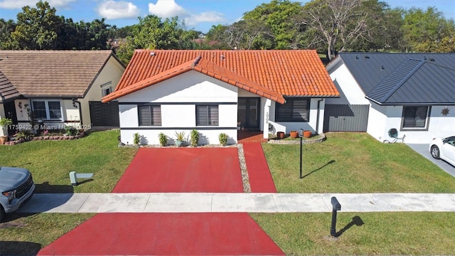 view of front of home with a front yard, a tile roof, and stucco siding